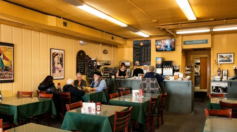 Diners seated at tables and a counter in a cozy, brightly lit restaurant with yellow walls.